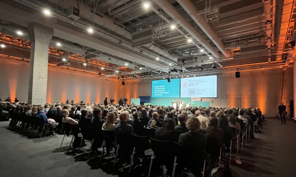 Eröffnung des Forums, mit einer Bühne und einerm Saal voller Personen. 